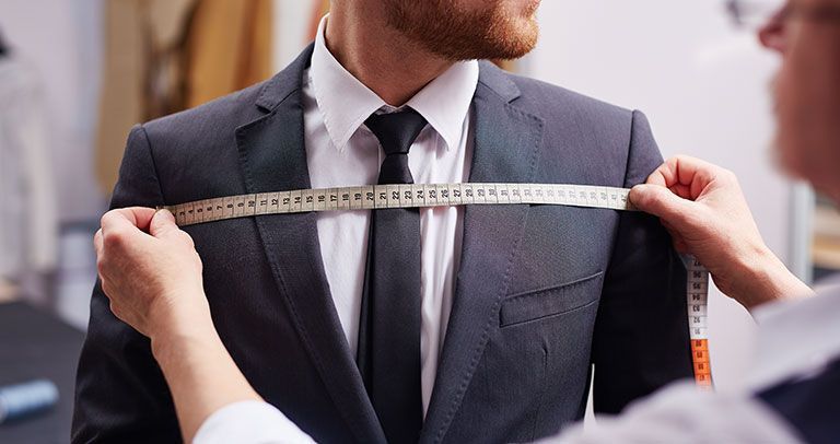 Testimonials - Derrick Dyas: A man in his suit getting his chest measured.